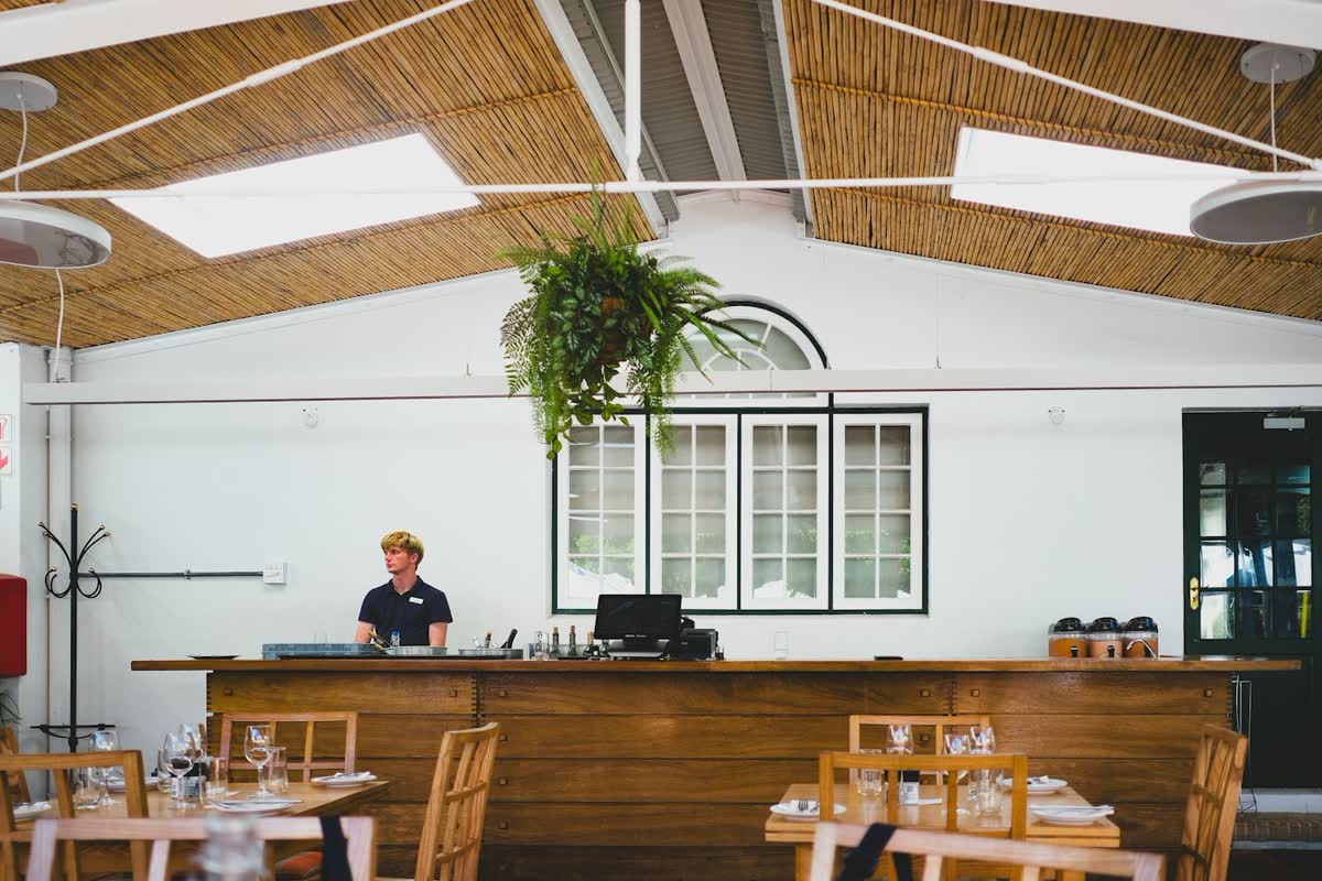 Atendente atrás do balcão de madeira de um restaurante