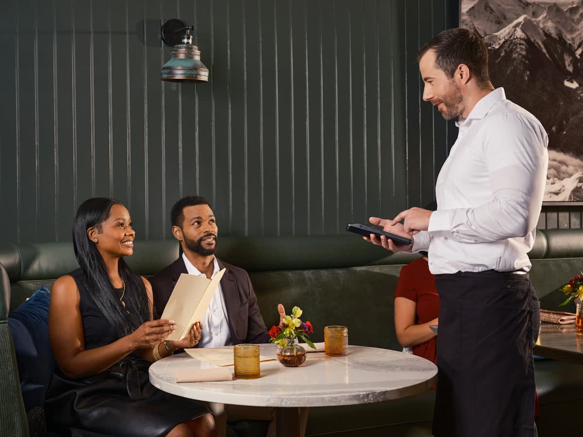Garçom anotando o pedido de um casal à mesa